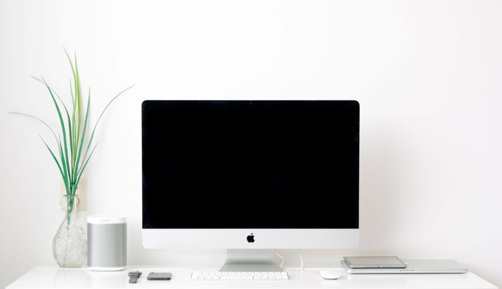 Komputer firmy Apple na tle białej ściany. Estetyka wykonania jako przykład holistycznego user experience. 